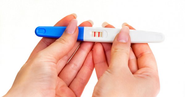 Положительный тест на беременность в руках у девушки