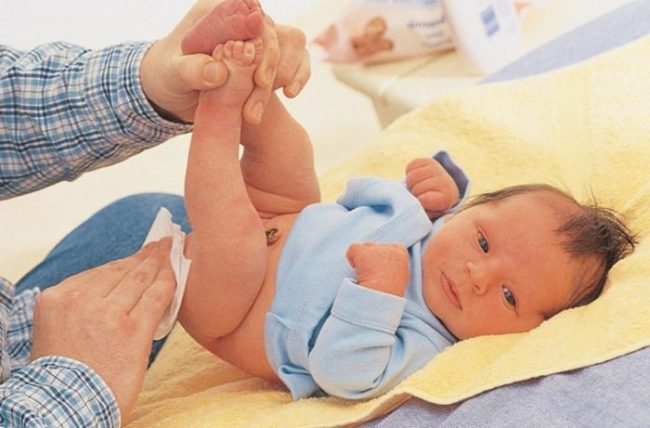 Новорождённый и белая салфетка в руке мужчины