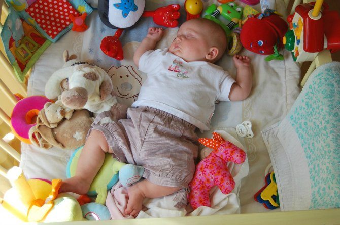 младенец спит среди игрушек