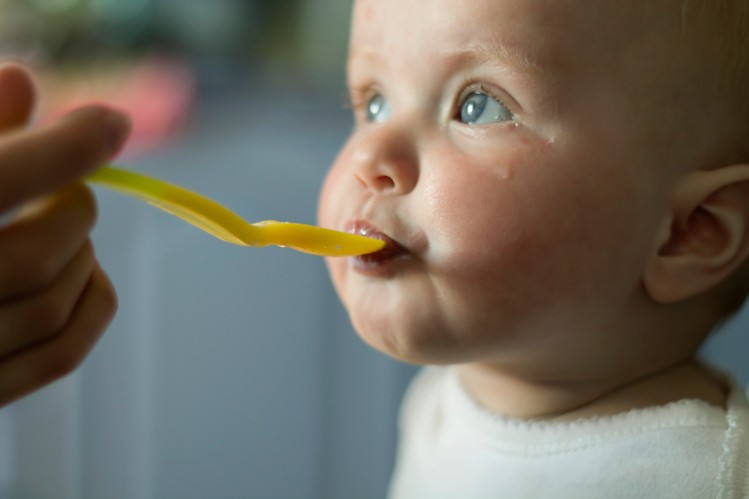 Малыш смотрит и ест с ложки