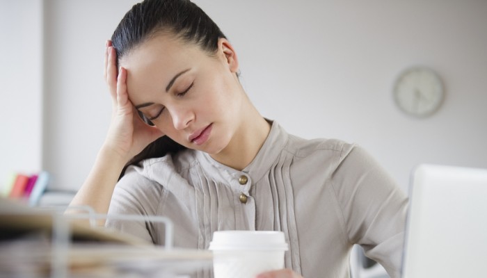 Woman exhausted at desk with coffee