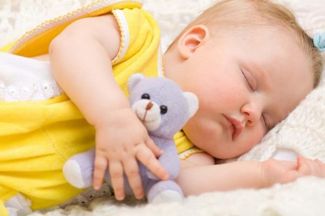 Ребенок спит и обнимает игрушку