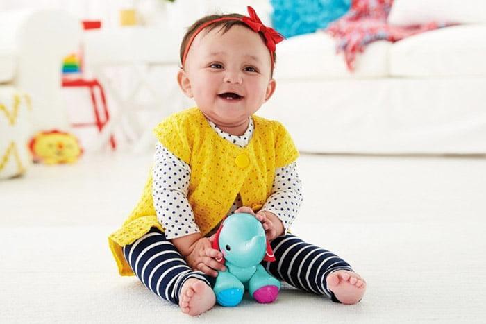 Ребенок девочка в 9 месяцев сидит и играет игрушками на полу