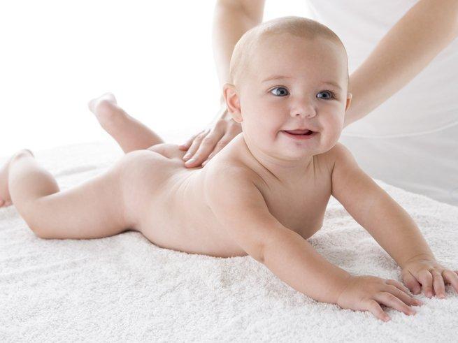 Мама делает массаж голенькому ребенку в 9 месяцев
