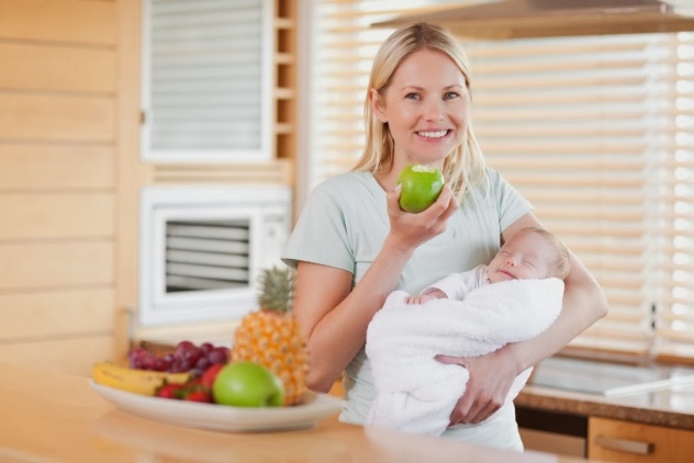 женщина держит младенца и ест яблоко
