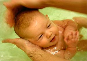 Папа купает малыша двух месяцев