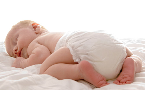 Новорожденный в памперсе лежит на животе