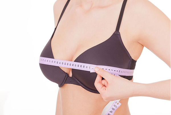 Женщина измеряет грудь сантиметром
