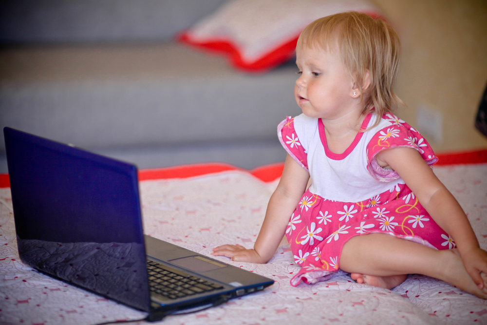 Малышка смотрит развивающий мультфильм на ноутбуке